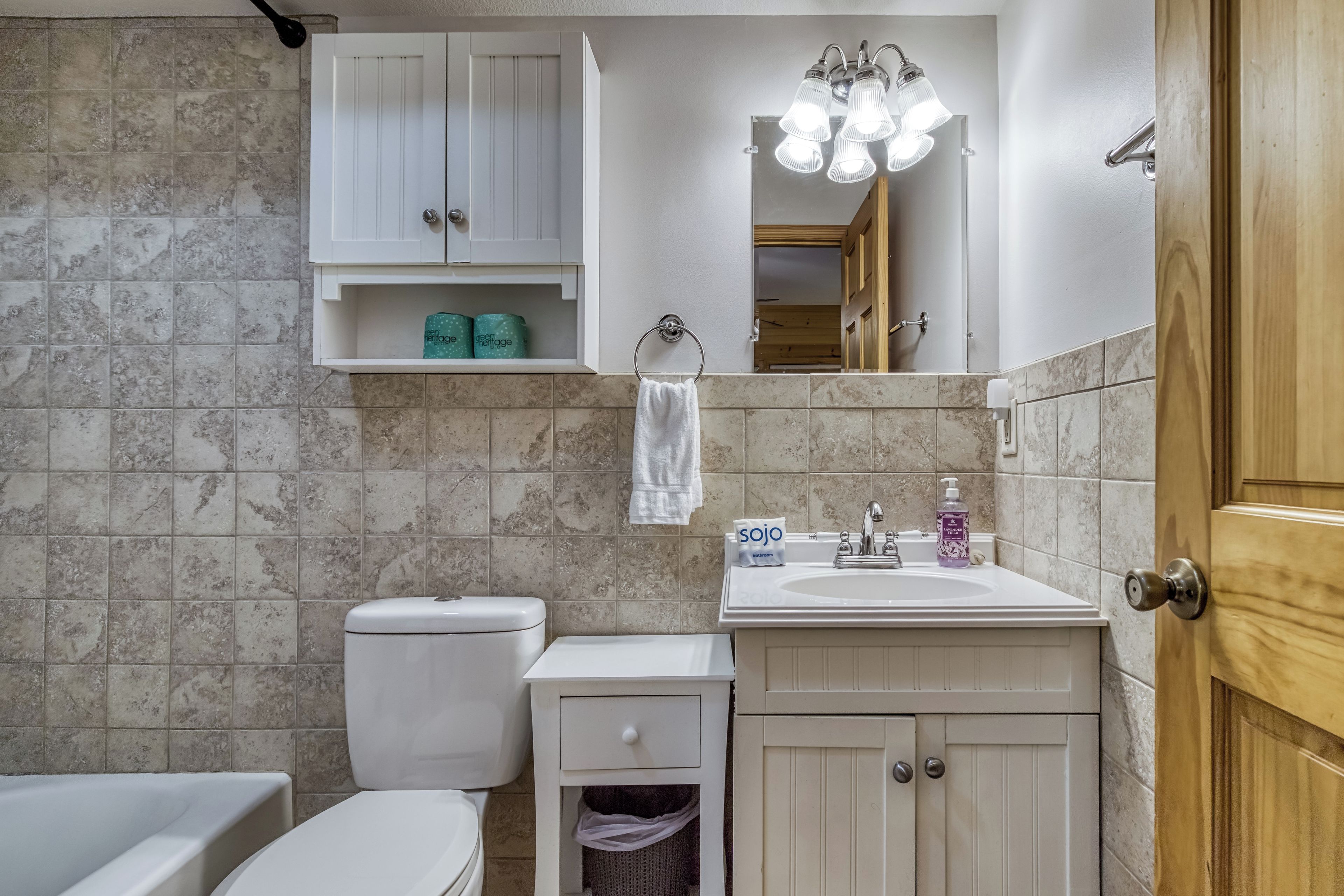 A bathroom with a toilet, sink, mirror, and cabinet.
