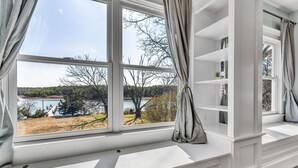 Une pièce dotée de grandes fenêtres, d’étagères intégrées et offrant une vue sur un lac et des arbres.