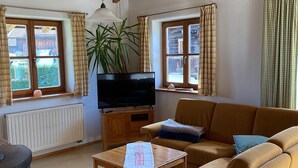 Een gezellige woonkamer met een bank, een televisie, een houten tafel en een radiator.