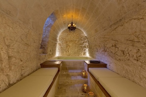 Ein Spa-Raum mit Steinwand, einer Mittelbadewanne und zwei Bänken.