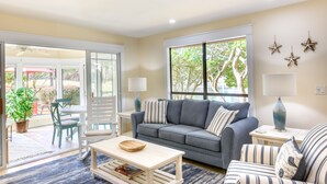 A living room with a grey sofa, striped cushions, a wooden coffee table, and a lamp.