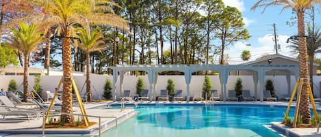 A swimming pool with lounge chairs and palm trees.