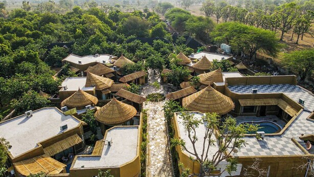 Ein Resort mit mehreren Gebäuden, jedes mit einem Reetdach, umgeben von üppiger Vegetation.