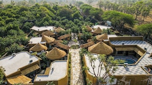 A resort with multiple buildings featuring thatched roofs, a central pathway, and a swimming pool.