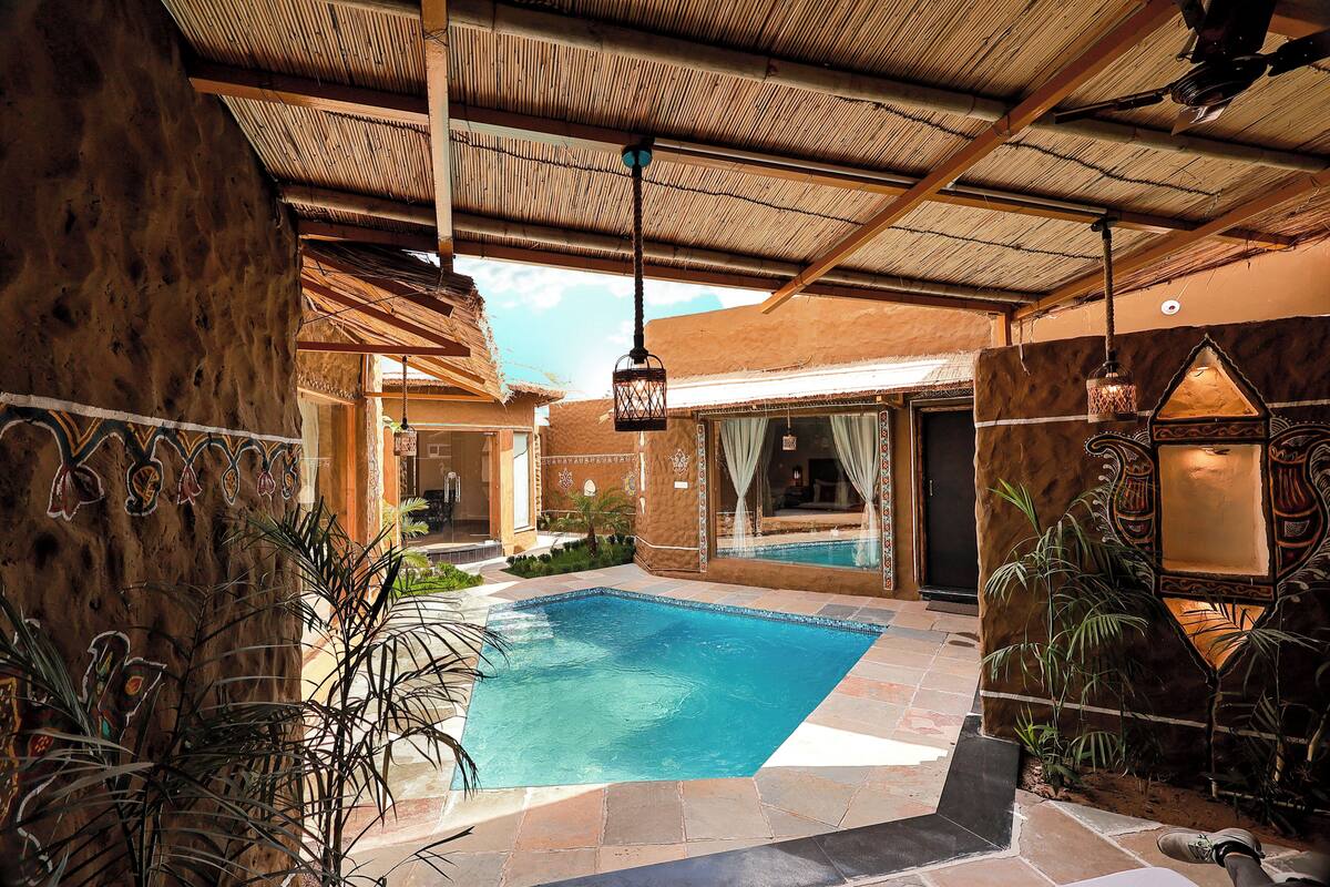 A pool area with a tiled floor, a thatched roof, and a wooden wall.