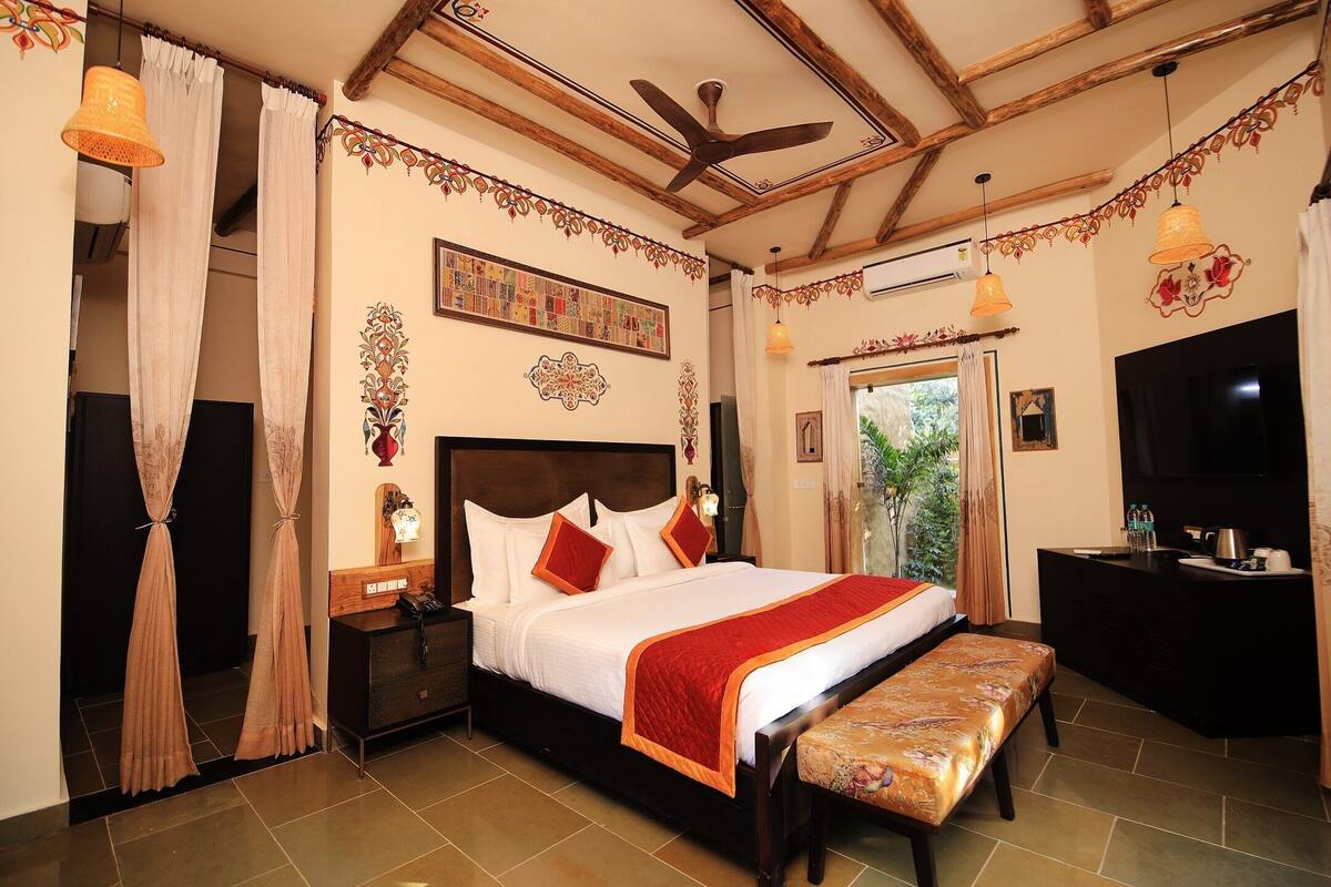 A well-appointed hotel room with a large bed, a wooden ceiling, a desk, and a television.