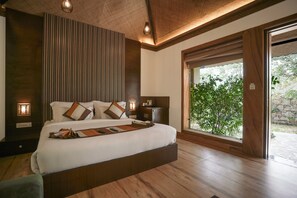 Quarto com uma cama grande, luminárias laterais, janela com vista para o verde e teto de madeira.