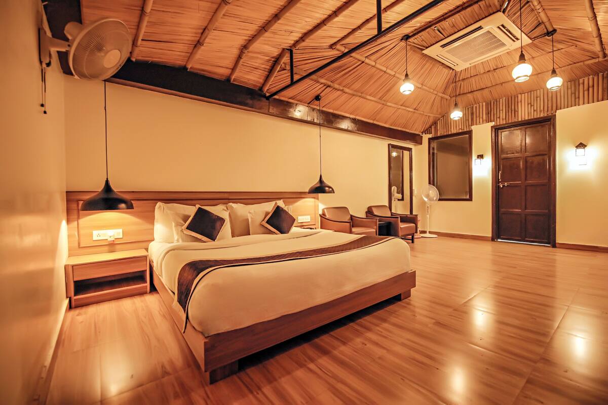 A spacious bedroom with a large bed, wooden flooring, a ceiling fan, and a wardrobe.