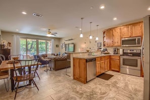 A kitchen with wooden cabinets, a microwave, an oven, and a dining area with chairs and a table.