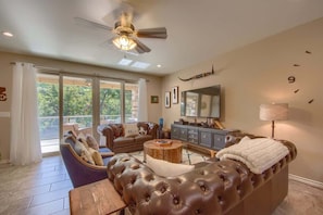 A living room with a sofa, armchair, coffee table, and a television. - RG 211 Guadalupe River Oasis (New Braunfels)