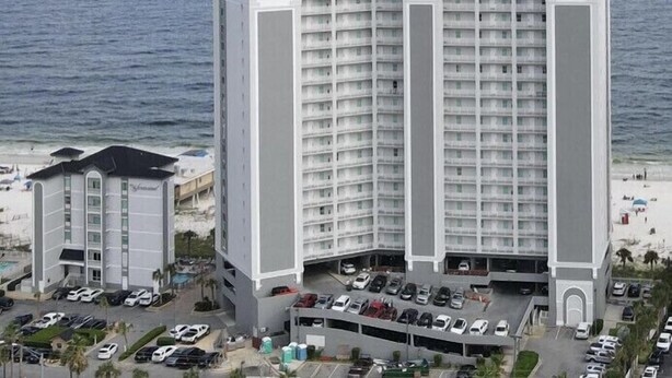 A high-rise hotel with multiple floors, a parking garage, and a view of the ocean.