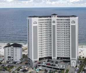 Een hoog hotel met meerdere verdiepingen, een parkeergarage en uitzicht op de oceaan.