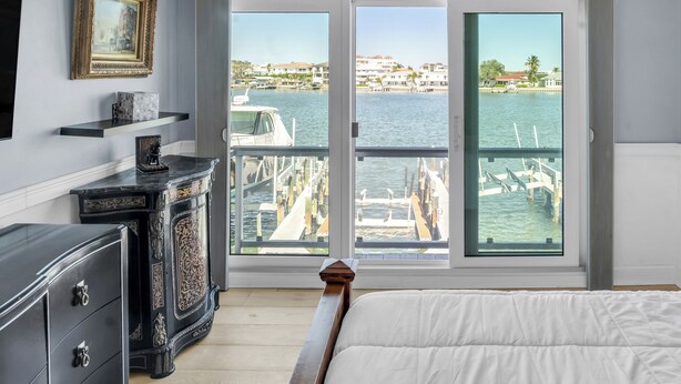 Un dormitorio con un amplio ventanal que da a un puerto deportivo y al agua.