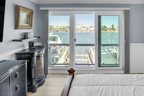 A bedroom with a large window overlooking a marina and water.