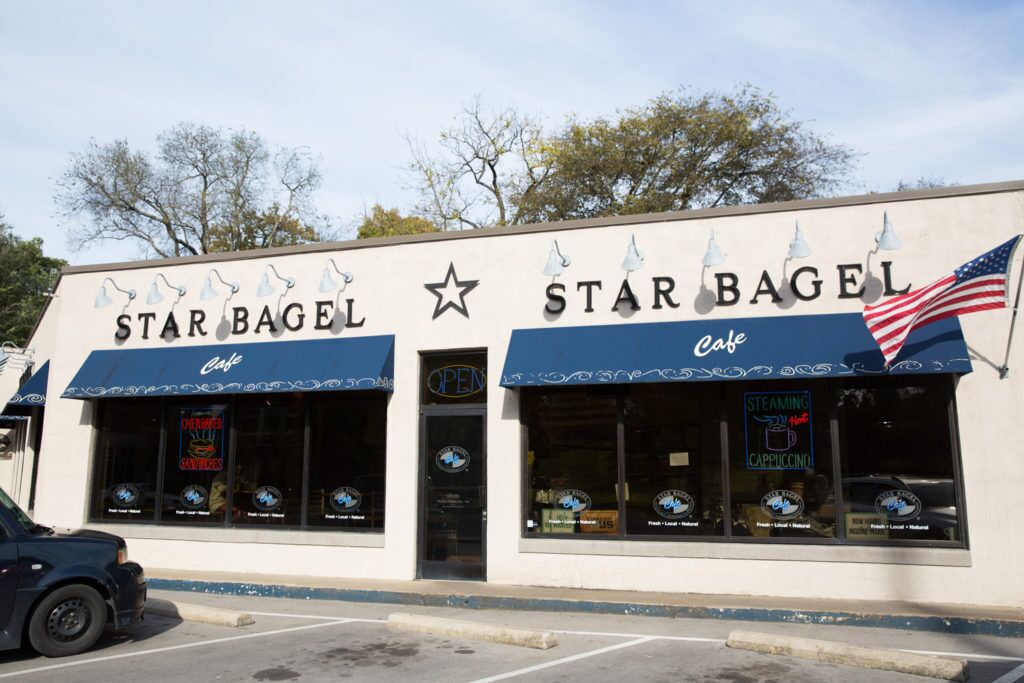 A StarBagel Cafe with a clear sign, American flag, and a parking lot in front.