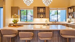 A modern kitchen with a large island, pendant lights, and bar stools. - Arcadia Luxury 4 Bedroom 4EnSuite Bath Heated Pool (Phoenix)