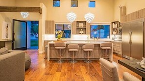 A modern kitchen with a central island, bar stools, a refrigerator, and pendant lights. - Arcadia Luxury 4 Bedroom 4EnSuite Bath Heated Pool (Phoenix)