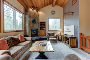 A cozy living room with a stone fireplace, leather furniture, and a television displaying 'Bennington Properties'.