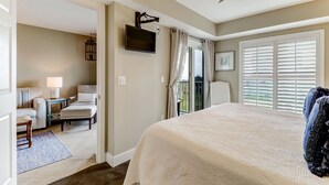A bedroom with a large bed, a TV mounted on the wall, a window with blinds, and a view of the outdoors. - Sea View is at the Beach! (Fernandina Beach)