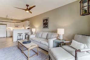 A modern living room with a sofa, a coffee table, and a dining area with a bar. - Sea View is at the Beach! (Fernandina Beach)