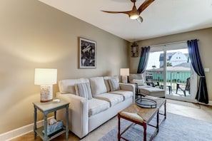 A living room with a sofa, two side tables, a bench, a ceiling fan, and a view of the outside. - Sea View is at the Beach! (Fernandina Beach)