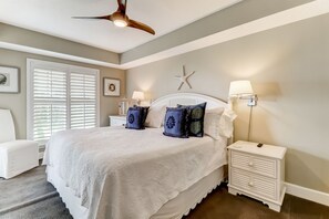 A bedroom with a large bed, two bedside tables, a ceiling fan, and a starfish decoration on the wall. - Sea View is at the Beach! (Fernandina Beach)