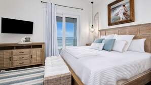 A bedroom with a large bed, a TV, a wooden dresser, and a view of the ocean. - On Tide Time - Beachfront | Private Pool | SAT-SAT (Panama City Beach)