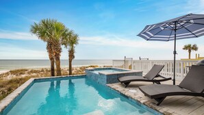 A swimming pool with lounge chairs and an umbrella, overlooking a beach with palm trees and a fence. - On Tide Time - Beachfront | Private Pool | SAT-SAT (Panama City Beach)