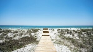 Un sendero de madera que conduce a una playa con cielos despejados.