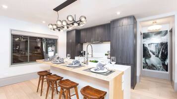 A modern kitchen with a central island, bar stools, and a large window.