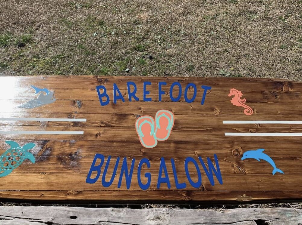 A wooden sign with the text "Barefoot Bungalow" and decorative fish illustrations.