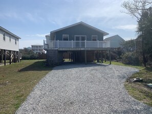 A two-story house with a covered porch and a gravel driveway. - Warm and cozy Beach Cottage. 3 houses from beach 5 houses from Middleton Park (Oak Island)
