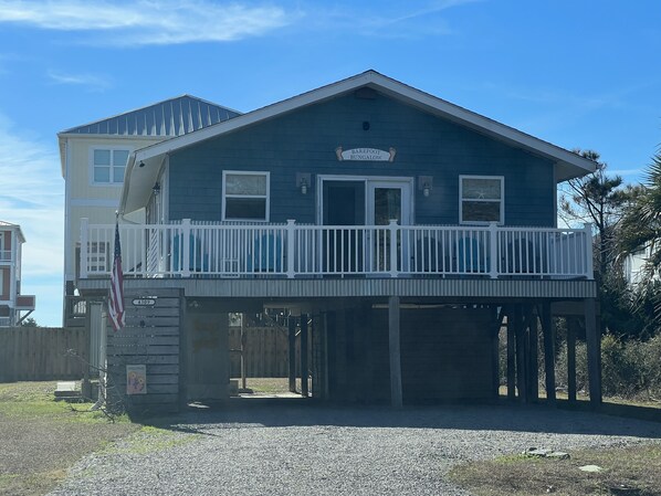 A two-story house with a balcony, a sign reading "Barefoot Bungalow," and an American flag. - Warm and cozy Beach Cottage. 3 houses from beach 5 houses from Middleton Park (Oak Island)