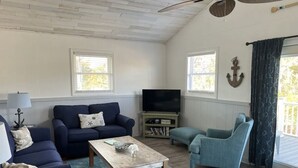 Ein Wohnzimmer mit Deckenventilator, zwei Sofas, einem Couchtisch und einem Fernseher.