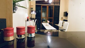 A modern kitchen with a dining table, chairs, and a plant. There are three containers labeled 'sugar', 'coffee', and 'tea'. - Forum Central City Loft with Free Wi-Fi and Parking (Canberra)