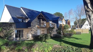 Een modern herenhuis met twee verdiepingen, een schuin dak, gevel van natuursteen en een verzorgde tuin.