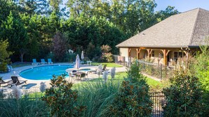 Ein Garten mit Swimmingpool, Liegestühlen und einem Holzgebäude mit Veranda.
