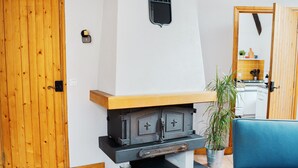 A room with a wooden door, a black stove, a blue chair, and a potted plant. - Le Woody - Proche Gare - Télétravail (Laval)