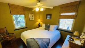 A bedroom with a bed, a chair, a nightstand, a lamp, and a window with blinds. - Central location with all the right amenities for the perfect vacation. (Tucson)