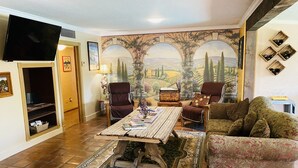 A living room with a large mural, a wooden coffee table, a sofa, and a TV. - Central location with all the right amenities for the perfect vacation. (Tucson)
