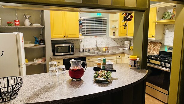 A kitchen with yellow cabinets, a stainless steel microwave, a gas stove, and a granite countertop. - Central location with all the right amenities for the perfect vacation. (Tucson)