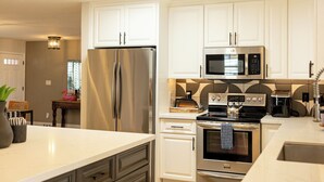 Une cuisine moderne dotée d’appareils électroménagers en acier inoxydable, de meubles blancs et d’un îlot central.