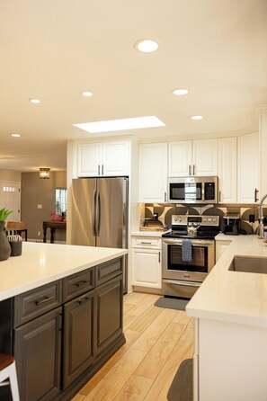A modern kitchen with stainless steel appliances, white cabinetry, and a central island.