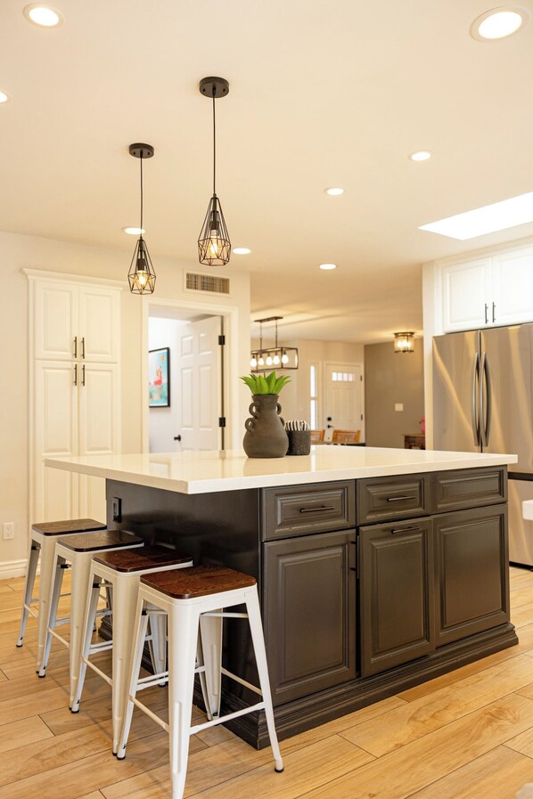 A modern kitchen with a central island, bar stools, pendant lighting, and a stainless steel refrigerator. - Luxury Kierland Oasis  Heated Pool & Spa  Putting Green  Sleeps 8 (Scottsdale)