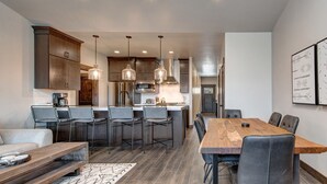 A modern kitchen with dark wood cabinets, stainless steel appliances, and pendant lighting. - Modern Mountain Luxury - Bonus room, Humidifier, Wi-Fi & Hot Tub! (Kamas)
