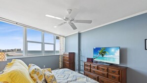 A bedroom with a bed, a television, a dresser, and a window with a view of the city. - Sunny Oceanfront Condominium, Short Walk to the Beach (Marco Island)