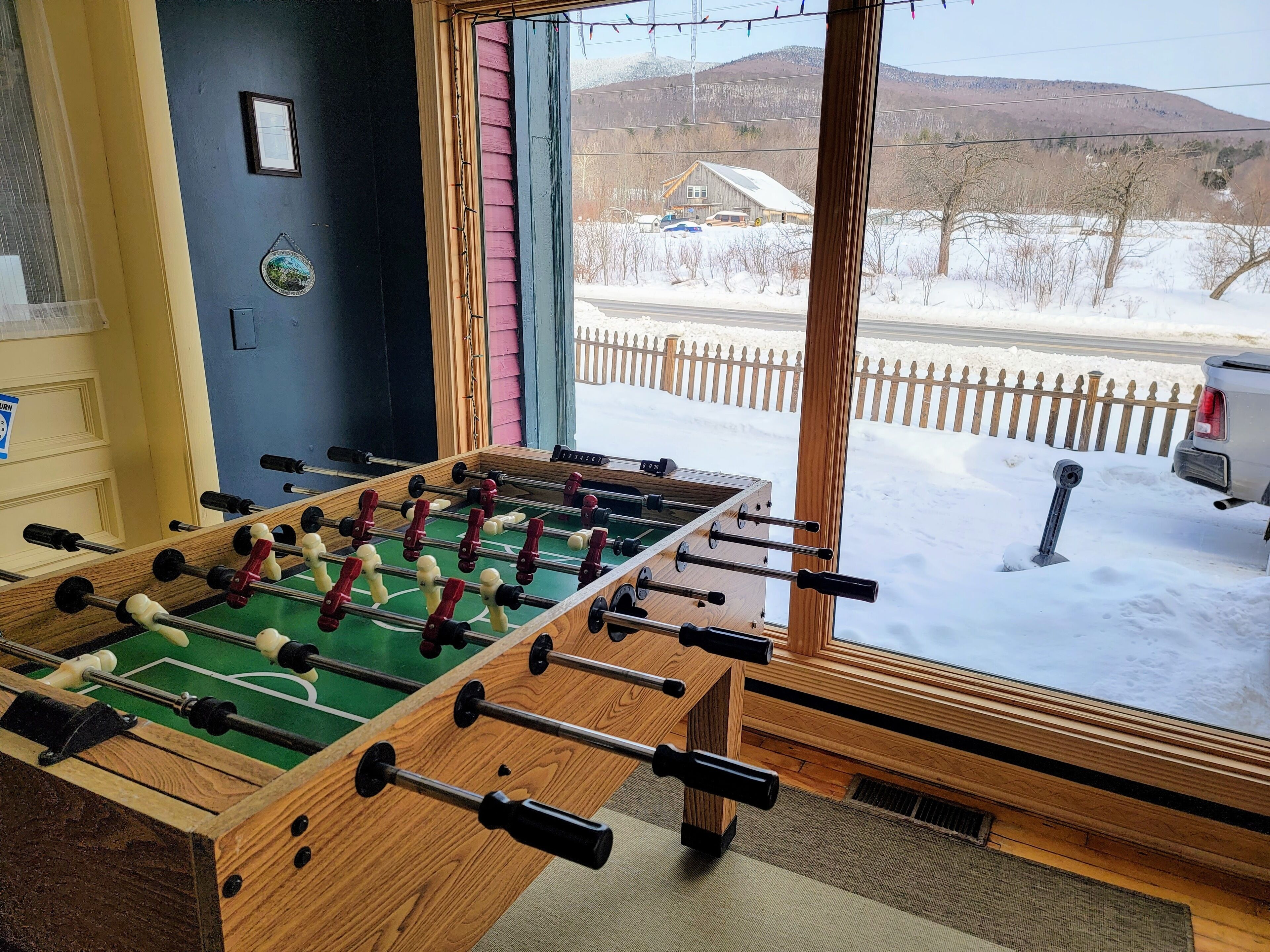 A foosball table in a room with a large window overlooking a snowy landscape.