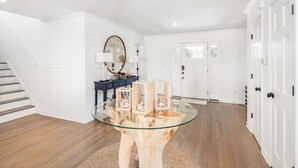 Ein modernes Interieur mit einem Glastisch, Holzboden, wei ßen Wänden und einer Treppe.