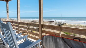 Eine Holzterrasse mit Blick auf Strand und Meer.
