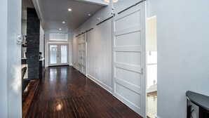A hallway with a wooden floor, white walls, and a large sliding door.